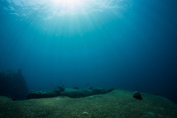Underwater seascape with natural sunlight through water surface and rocks on the seabed.underwater...