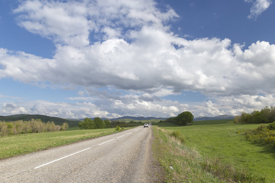 One car in a road in the mountains under the sky with clouds and clouds