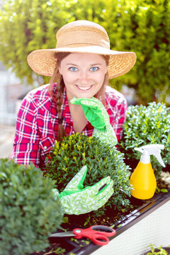 Fröhliche Frau im Garten beim Pflanzenpflege