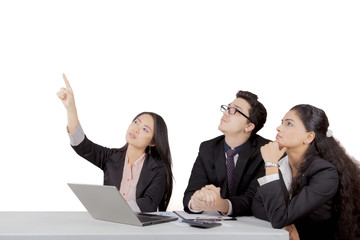 Japanese businesswoman pointing to blank space while other team members pay attention