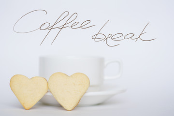 Coffee cup with saucer and two heart shape cookies on white background. Coffee break lettering.