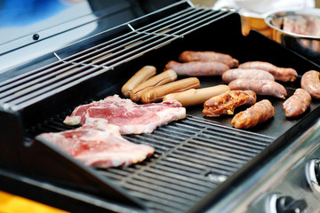 Delicious and tasty sausages and steaks cooking on a barbecue grill
