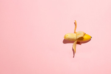Sweet juicy opened small banana on pink table. Sexual life libido, penis size and potency concept