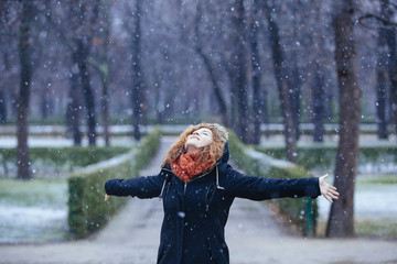 young woman on a winter day under snowflakes in the park