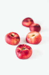 Fototapeta na wymiar Selective focus composition of several fresh flat donut nectarines, red saturn nectarines or ripe fuzzless vineyard peaches on white background