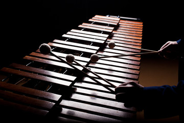 The hands of a musician playing the marimba in dark tones
