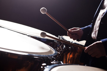 The hands of a musician playing on a timpani closeup in dark tones