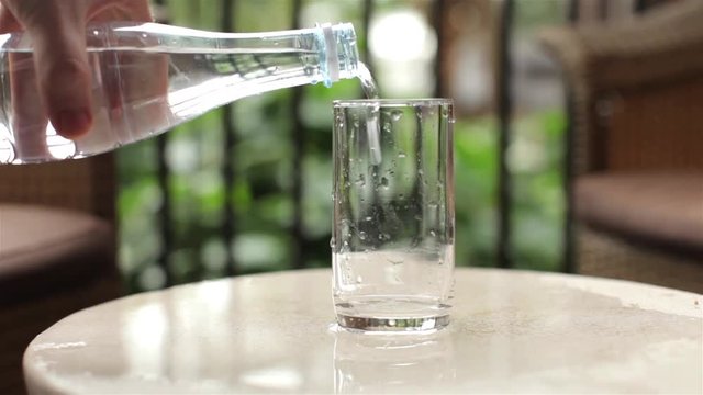 close-up. man pours clean water from a bottle into a glass
