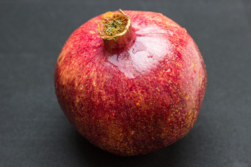 One whole pomegranate fruit isolated on wood background