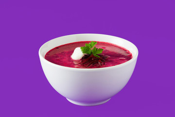 Beet soup in white bowl isolated on purple background. 