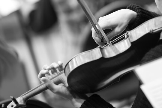 Hands of a girl playing the violin closeup in black and white tones