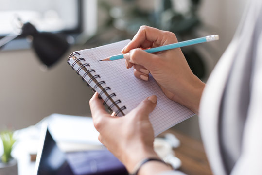 cropped image of businesswoman writing something in notebook
