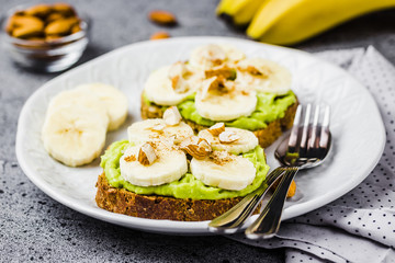 Avocado banana toasts with almonds on concrete background. Selective focus ,copy space.