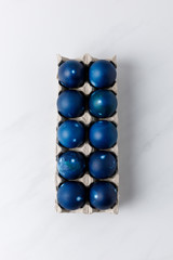 top view of blue painted easter eggs in egg tray on white tabletop