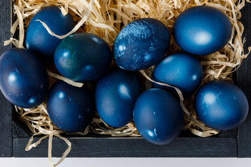 Fototapeta na wymiar top view of blue painted easter eggs in wooden box with decorative hay