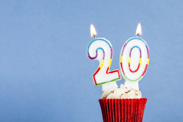 Number 20 birthday candle in a cupcake against a blue background