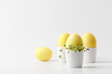 Yellow painted easter eggs in egg stands on white