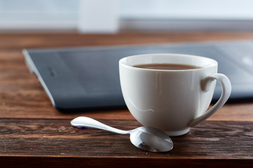 Teacup with spoon on dark wooden background, shallow depth of field.