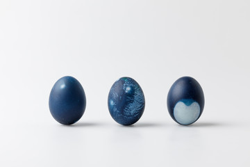 Three blue painted easter eggs on white surface