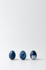 three blue painted easter eggs on white
