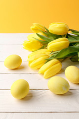 yellow painted easter eggs with bouquet of tulips on wooden tabletop