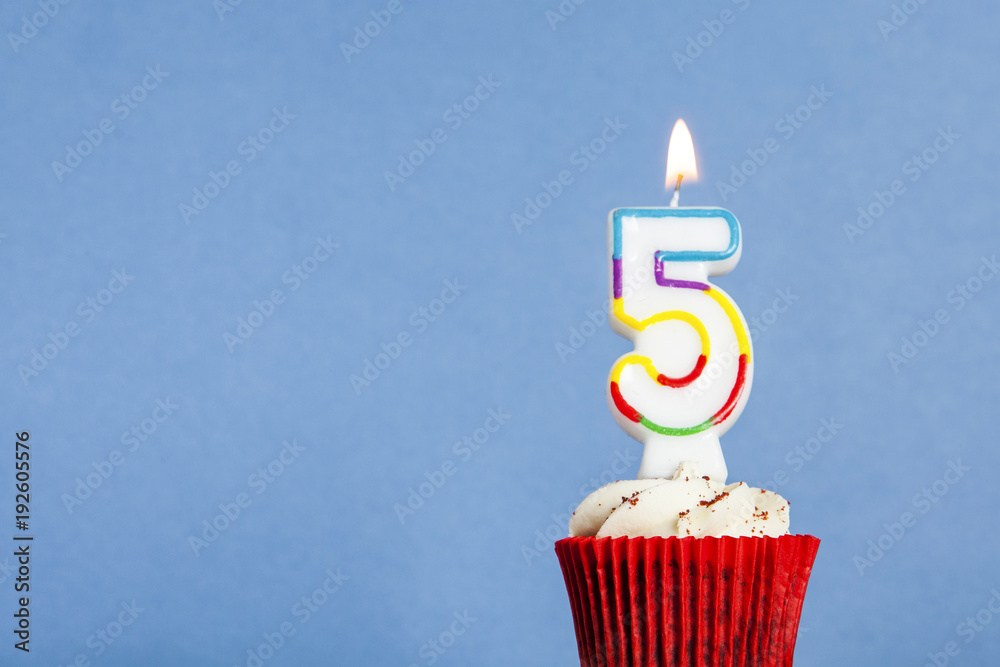 Wall mural number 5 birthday candle in a cupcake against a blue background