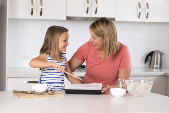 young mother and sweet little daughter baking together happy at home kitchen in family lifestyle concept