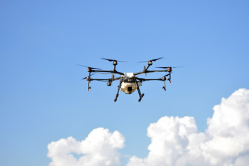 Flying agriculture drone, photo image of agriculture drone carry a tank of liquid fertilizer flying in the blue sky prepare to spray it in farming area, agriculture technology, drone technology