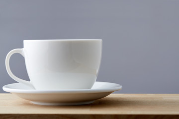 Selective focus side close up view white teacup and saucer isolated on grey background