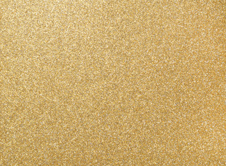 Glitter grain of gold on rough golden plate, closeup photo on rough golden plate surface show a...