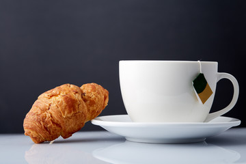 Breakfast with te and croissants on grey background, close-up