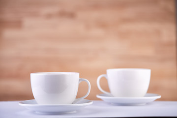 Two white porcelain teacups on wood texture surface show clean and simple design ideas. Selective focus