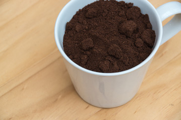 Coffee grounds in a white cup on  a wooden table for breakfast