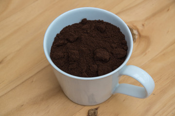 Coffee grounds in a white cup on  a wooden table for breakfast