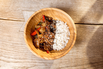 Asian wok rise meal served in the wooden plate on the table