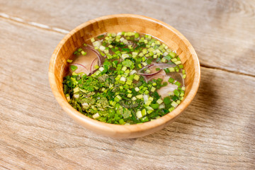 Onion asian soup served in the wooden plate on the table