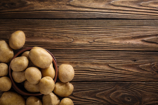 Fresh potato food. Pile of raw potatoes lying  on old wooden table. Concept of food background. Free place for text, top view.