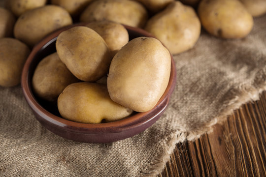 Fresh potato food. Pile of raw potatoes lying  on old wooden table. Concept of food background. Free place for text, top view.