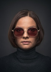 Fototapeta na wymiar Beautiful young girl with sunglasses on dark background.