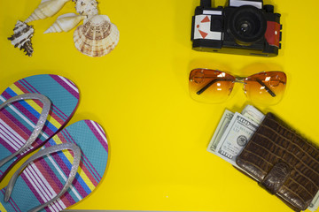 Bright yellow one-color background with tourist's accessories, top view. Planning a vacation with a map, wallet, camera, sneakers and sunglasses. Travel or tourism concept.