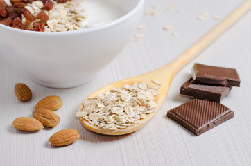 Oatmeal with raisins and yogurt. Oatmeal in the wooden spoon. Almond, chocolate