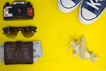 Vacation planning. Bright yellow one-color background with tourist's accessories mock up, top view.Travel or tourism concept.