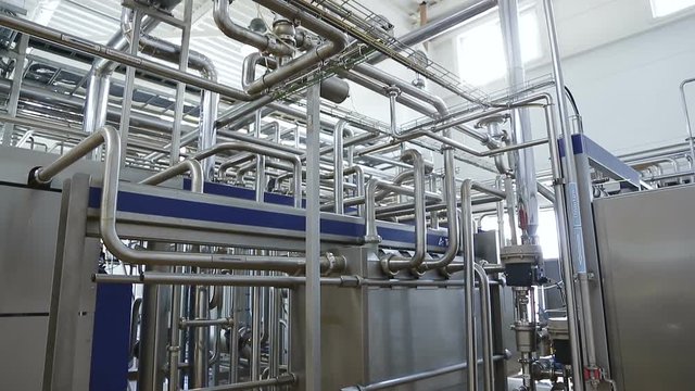 Pipeline in a modern dairy factory. Modern complex technological industrial equipment. Plurality of pipelines, gauges and faucets. Shot in motion. Vertical panorama.