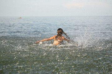 Spray with water. Girl having fun bathing in the sea.