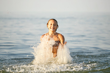 Obraz premium Spray with water. Girl having fun bathing in the sea.