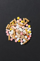 Medication white colorful round tablets arranged abstract on black color background. Aspirin, capsule pills design. Health, treatment, choice healthy lifestyle concept. Copy space for advertisement.