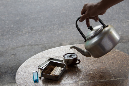 The lighter, coffee cup, tobacco and old pot put on the wood table.