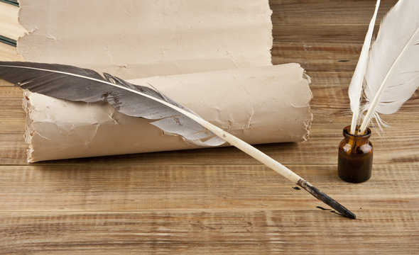 Old paper and feather with ink on a wooden table