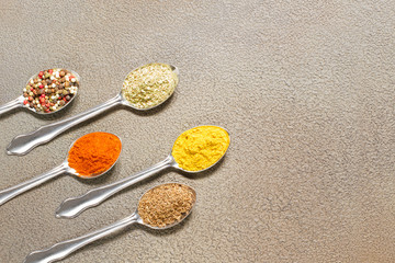 Various spices in a spoon on grey background