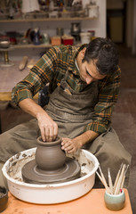 Fototapeta na wymiar Artist makes clay pottery on a spin wheel